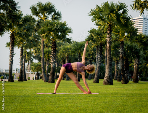 Beautiful young woman practic yoga at the beach. Early morning exercise