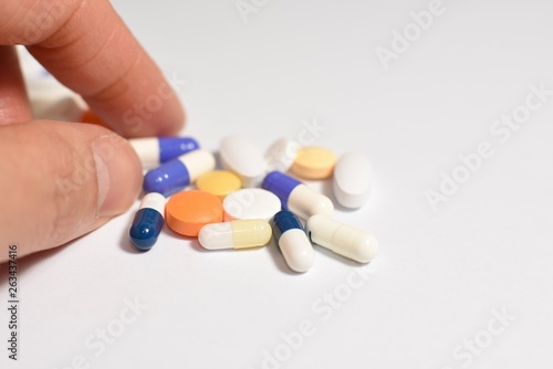 Various medical pills and capsules picked up with hand