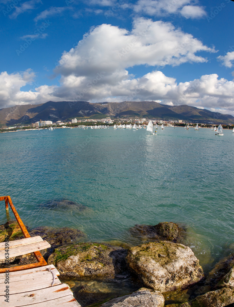 The Resort Of Gelendzhik. Annual children's yacht regatta. Many yachts with white sails in Gelendzhik Bay on the background of the resort and the mountains. Markoth ridge. 