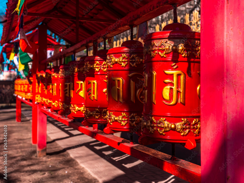 Red prayer wheels in a Buddhist temple. Buddhist prayer wheel Hurde. Prayer drums in a Buddhist sanctuary