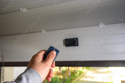 Garage door PVC. Hand uses remote controller for closing and opening garage door