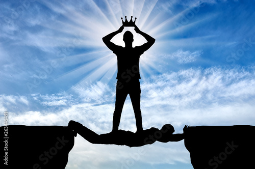 Selfish man puts his crown on his head, he is on the man in the form of a bridge over the abyss photo