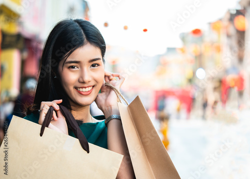 Asian women are addicted to shopping or shopaholic shopping in the old town with colorful paper shopping bags during the discount season with copy space and blur city or tourist background, Soft tone.