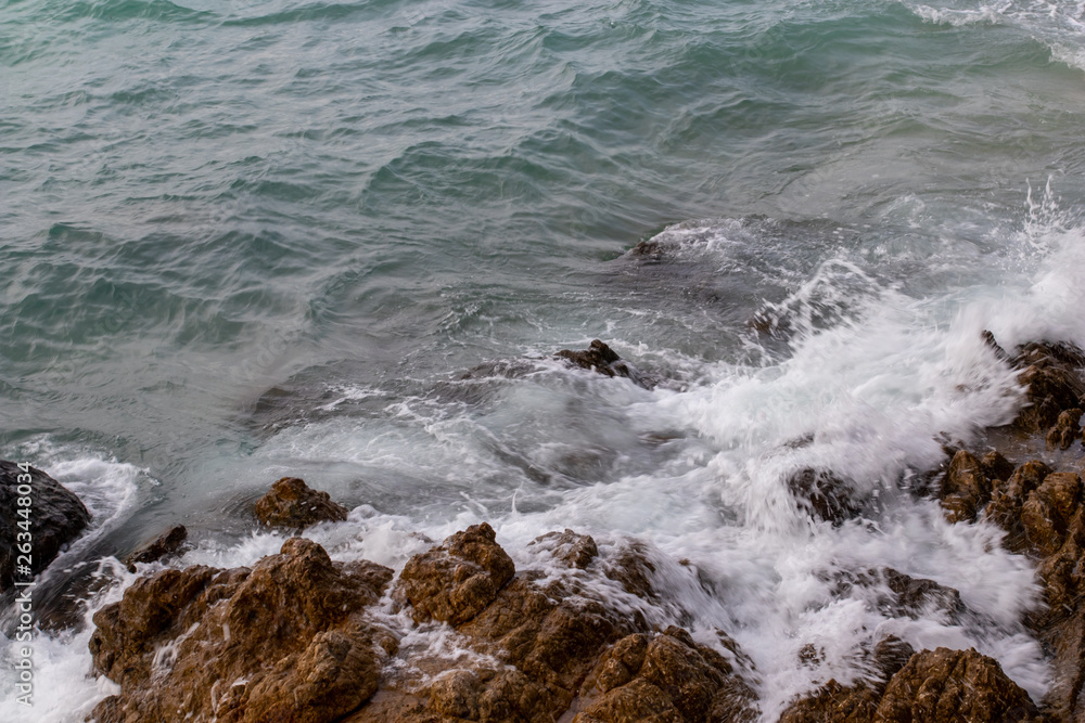 The ocean waves hit the rocks on the rocky beach in the morning, Ocean waves hit the rocks at the beach.