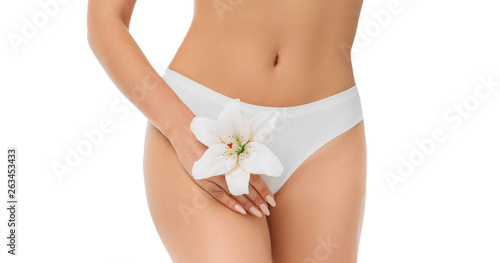 slim woman dressed in white panties, holding a lily in her hands, close-up. Gynecology, menstruation, the concept of genital health