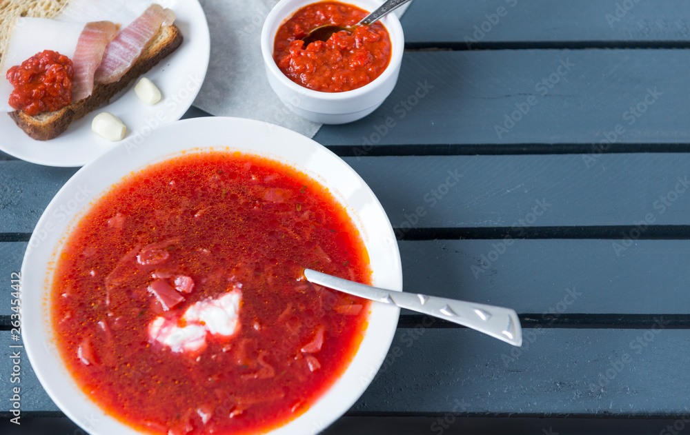 plate of borscht, ketchup, lard on a piece of bread on a wooden gray background plate of borscht, ketchup, lard on a piece of bread on a wooden gray background