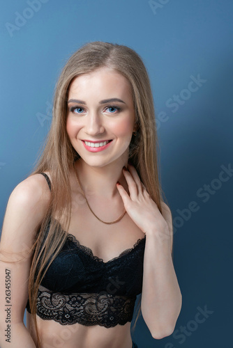 Young beautiful girl in black bra with hands on neck.