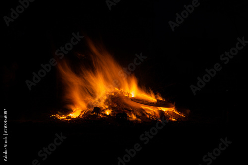 Bonfire burning trees at night. Large orange flame isolated on a black background