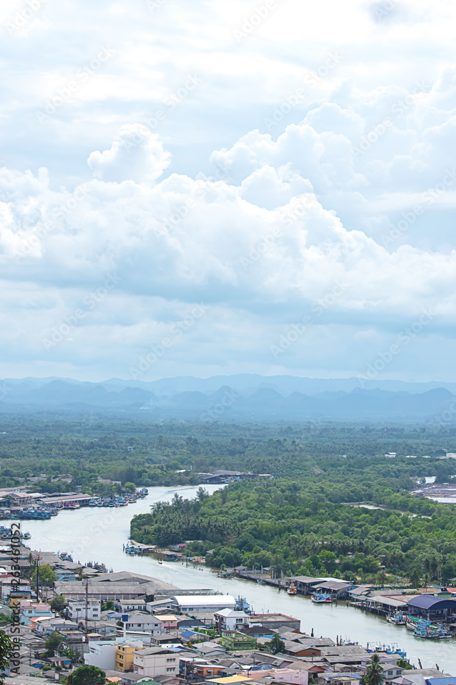 The point of view of Cityscape and a boat parked in Tha Taphao river , Background mountains and  sky at Mutsea Mountain Viewpoint in Chumphon , Thailand.
