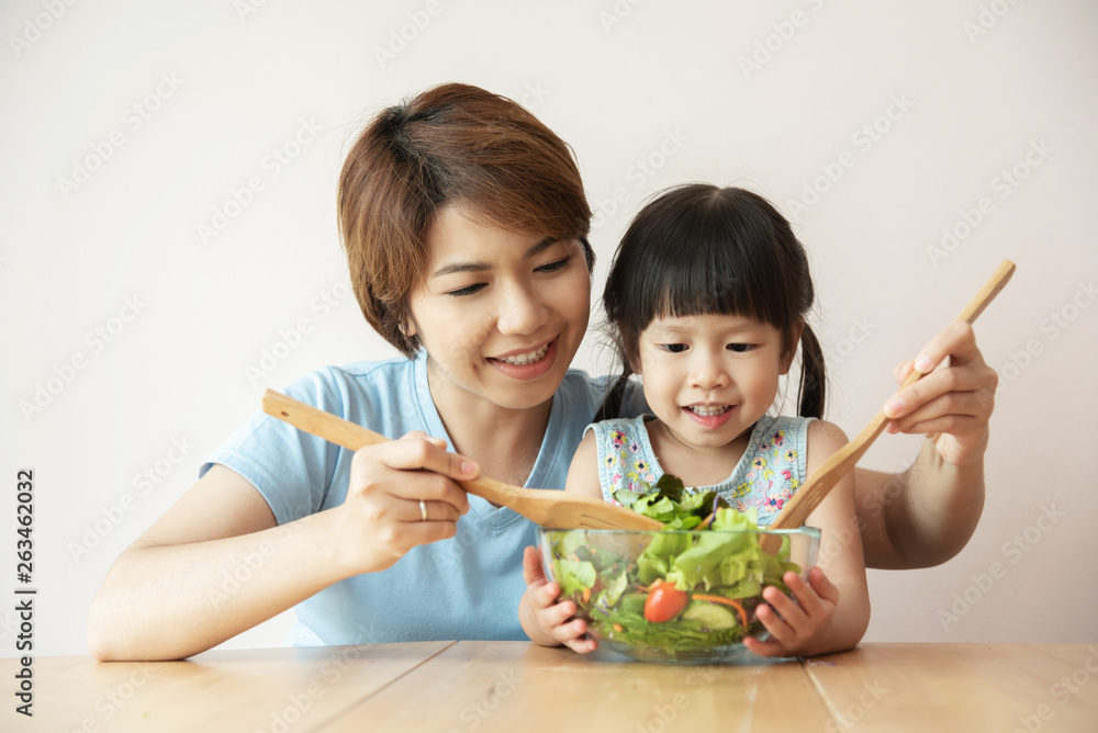 Happy Asian Young Mother and little girl cooking salad. Happy Asian Young Mother and little girl cooking salad.