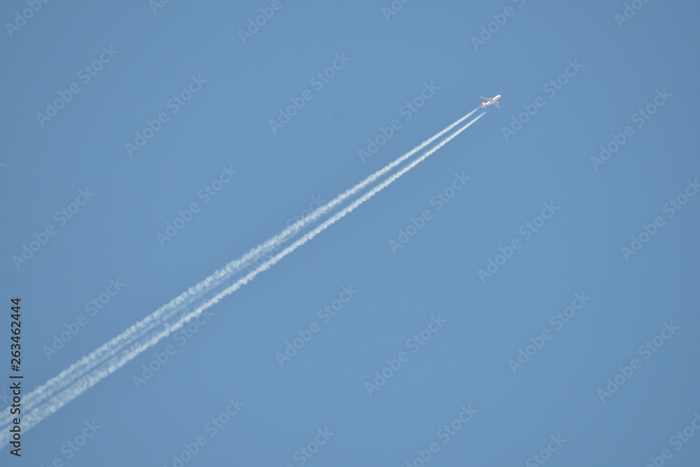 Commercial aircraft at very high altitude with white contrail on cloudless blue sky Commercial aircraft at very high altitude with white contrail on cloudless blue sky