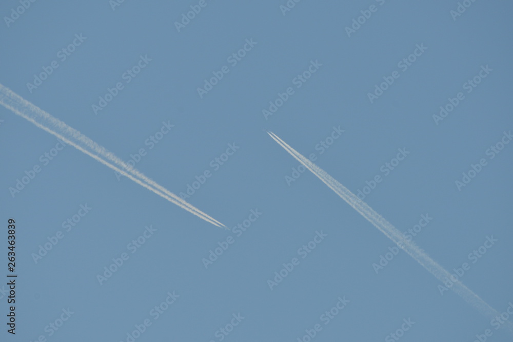 Commercial aircraft at very high altitude with white contrail on cloudless blue sky Commercial aircraft at very high altitude with white contrail on cloudless blue sky