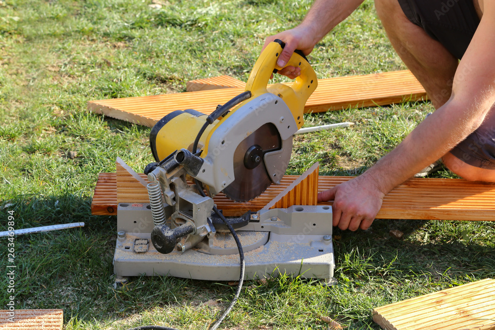 A worker saw wood with a chop saw A worker saw wood with a chop saw