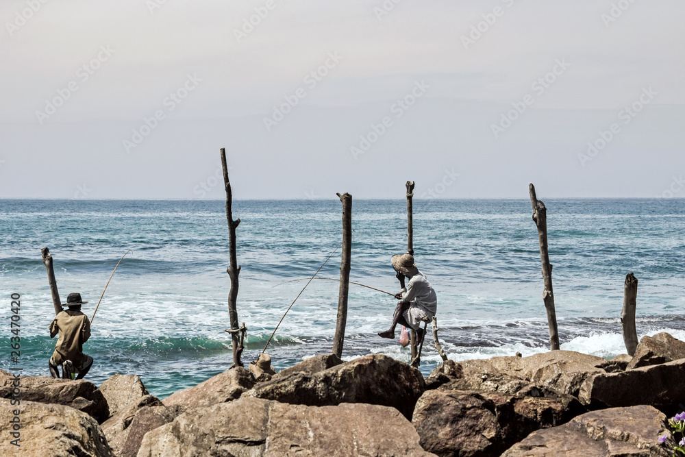 fisher man sitting on wood stick at coast in Mirissa, Sri Lanka fisher man sitting on wood stick at coast in Mirissa, Sri Lanka