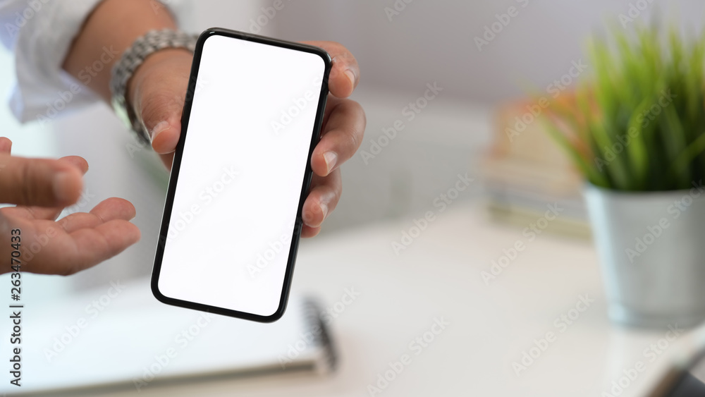 Anonymous man showing blank screen mobile smart phone on workspace Anonymous man showing blank screen mobile smart phone on workspace