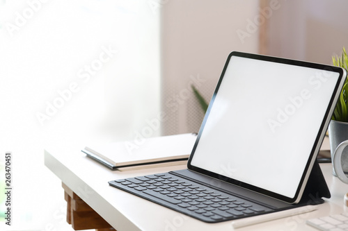 Mock up blank screen tablet with smart keyboard on white desk