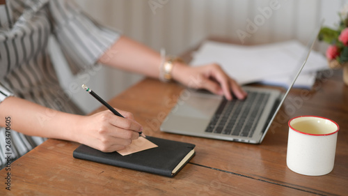 Businesswoman sitting at office and writing on sticky paper notes on desk