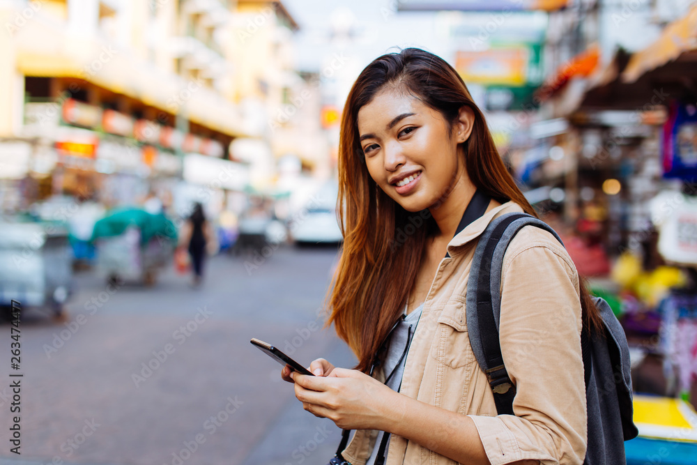 Young Asian female tourist woman using a mobile phone in Bangkok, Thailand. Calling a cab or finding information during traveling concept Young Asian female tourist woman using a mobile phone in Bangkok, Thailand. Calling a cab or finding information during traveling concept