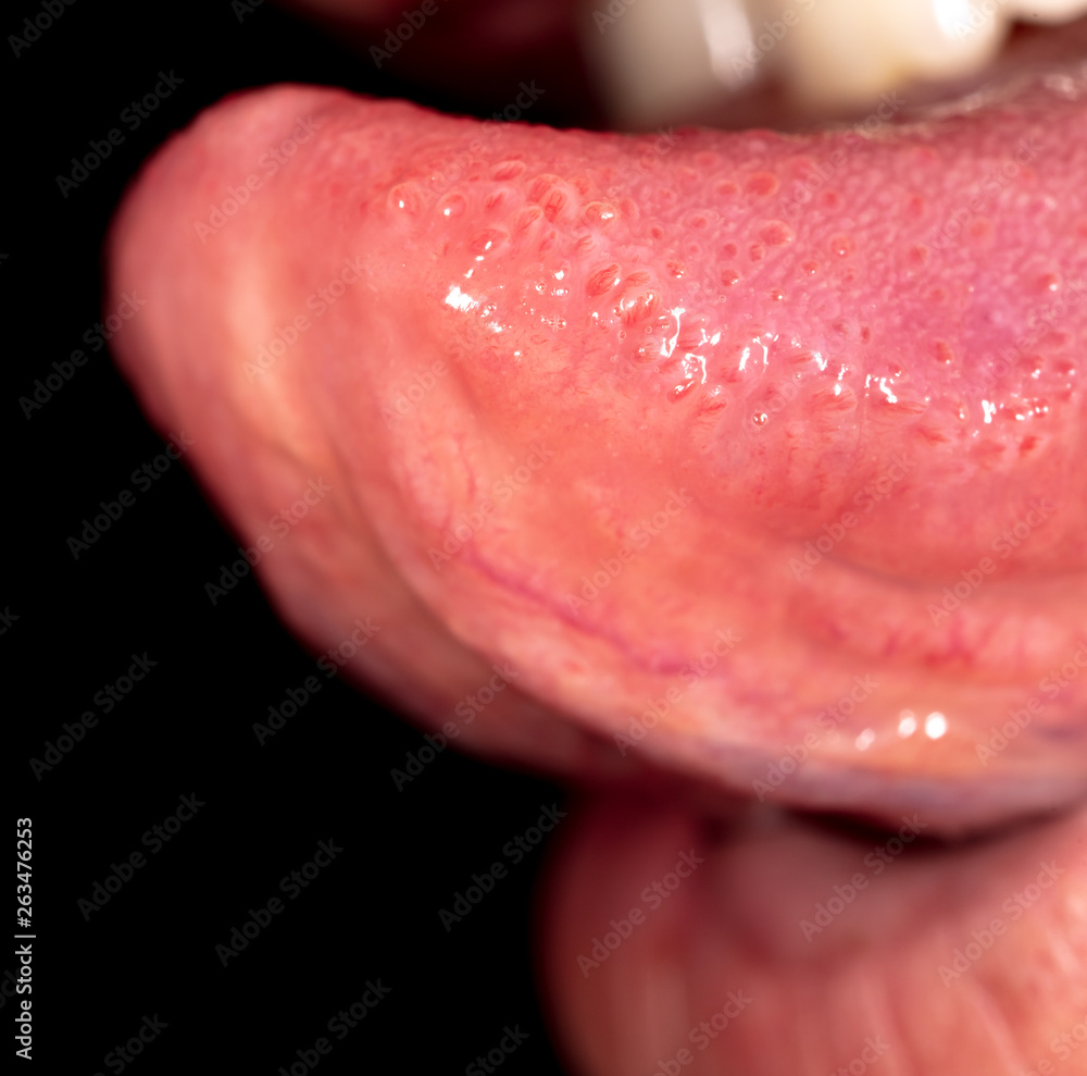 Tongue in the mouth of a man on a black background.