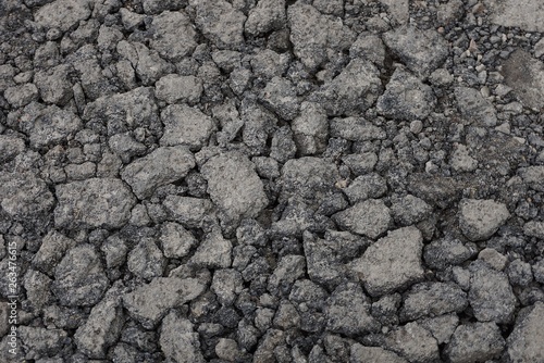 gray stone texture of asphalt pieces with cracks on the road