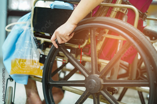 Asian middle-aged lady woman patient sitting on wheelchair with urine bag in the hospital ward : healthy medical concept  photo