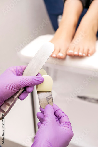 Manicurist work on a woman client feet, make her nails look beautiful. Salon pedicure procedure in process. Professional works in gloves for sterility