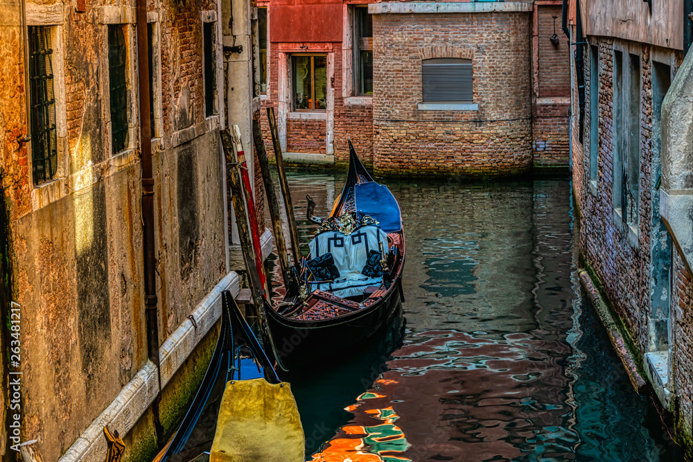 Beautiful morning view of a narrow street canal with a gondola between old houses in Venice, Italy