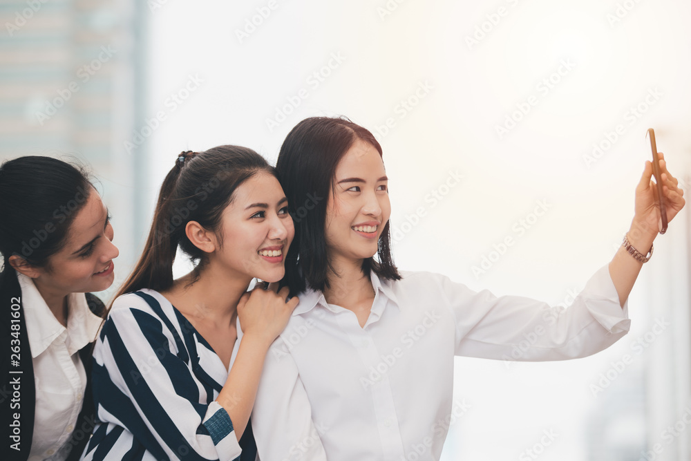 Obraz premium Asian lifestyle businesswoman best friends smiling and having fun walking selfie at the city