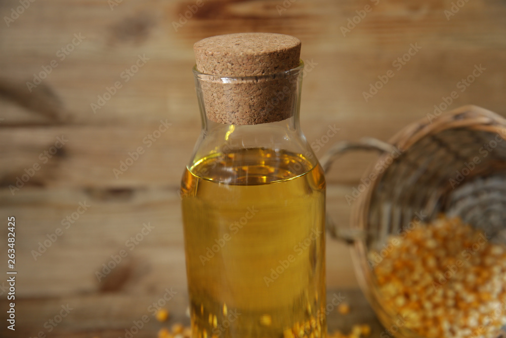 corn oil in a bottle close-up with a basket of corn kernels scattered on a wooden rustic background corn oil in a bottle close-up with a basket of corn kernels scattered on a wooden rustic background