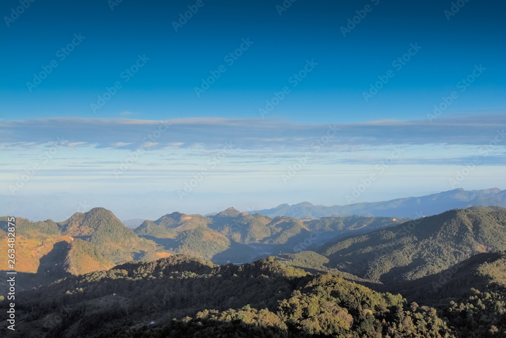 Mountain view morning of top hills around with soft fog and blue sky background, sunrise at top view point highest of Doi Ang Khang, Chiang Mai, northern of Thailand.