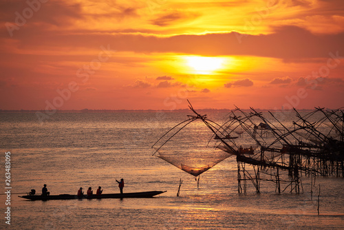 Tourists on the long tail boat taking photography of net fishing during sunrise in the morning