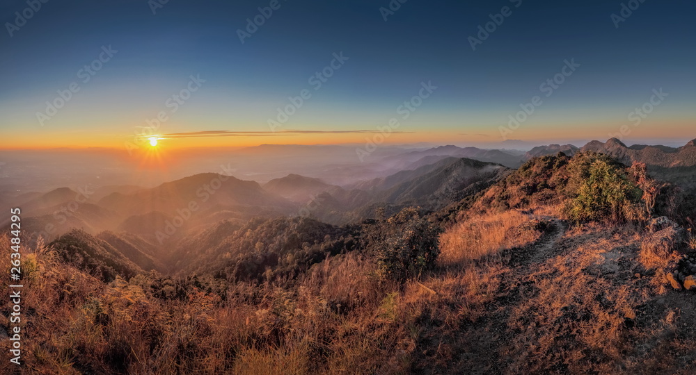 Mountain view misty morning of top hills around with the soft fog with yellow sun light in the sky background, sunrise at top of Doi Ang Khang, Chiang Mai, northern of Thailand.