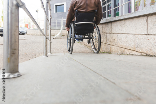 Man in a wheelchair use a wheelchair ramp.