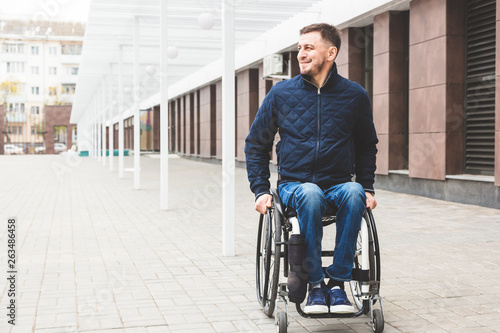 Young man in a wheelchair against the backdrop of a modern high-rise building. © xartproduction