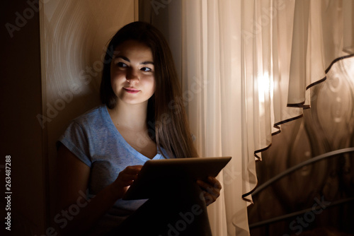 Young woman sitting by the window and using digital tablet at ho