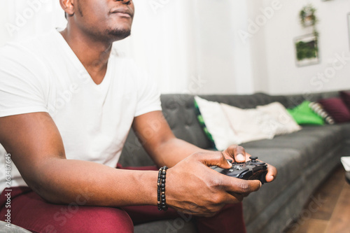Young African American man playing a game console at home.