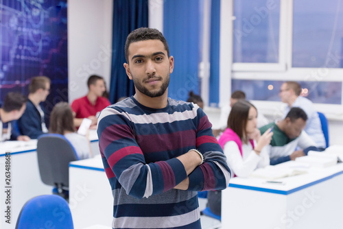 Students life on the campus.Portrait of male college student smiling and looking at camera during class in the classroom. University male african american student standing  in classroom.