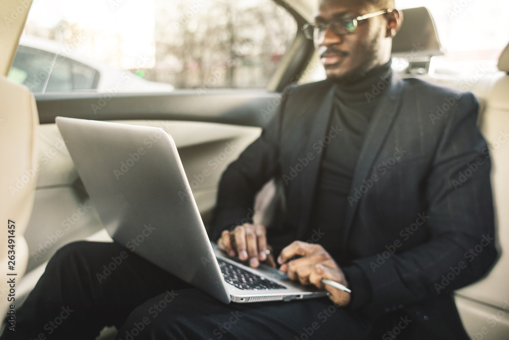 Man in a business suit write on laptop in the salon of an expensive car with leather interior. Man in a business suit write on laptop in the salon of an expensive car with leather interior.