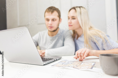 Lovely young couple, using a laptop and choosing a new apartment.