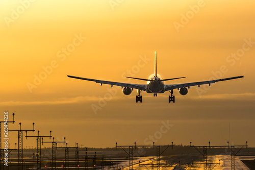 Airplane landing to airport in sunset
