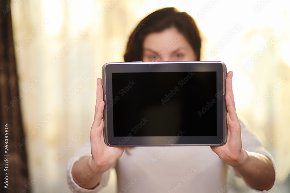 The girl is holding a tablet. The girl has a computer with a screen in her hands. Hands hold the display with an empty space.