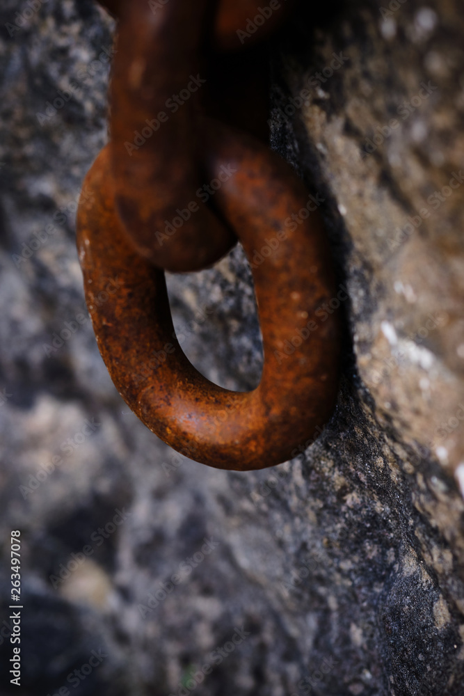a large rusty chain hanging from a stone a large rusty chain hanging from a stone