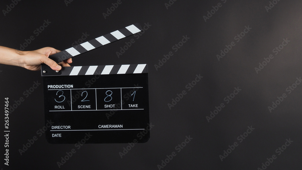 Hand is holding Black Clapperboard or movie slate with write in number. it use in video production ,film, cinema industry on black background.
