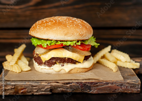 Delicious homemade hamburger with beef, salad, cheese, cucumber and french fries chalkboard on wood background