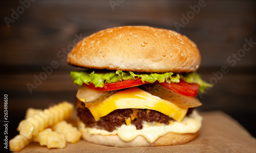  Delicious homemade hamburger made of beef, salad, cheese, cucumber and french fries on a wood background