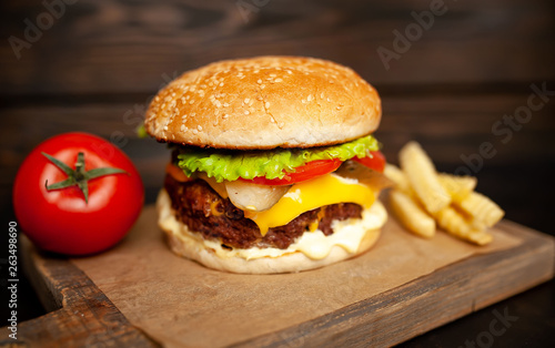  Delicious homemade hamburger made of beef, salad, cheese, cucumber and french fries on a wood background