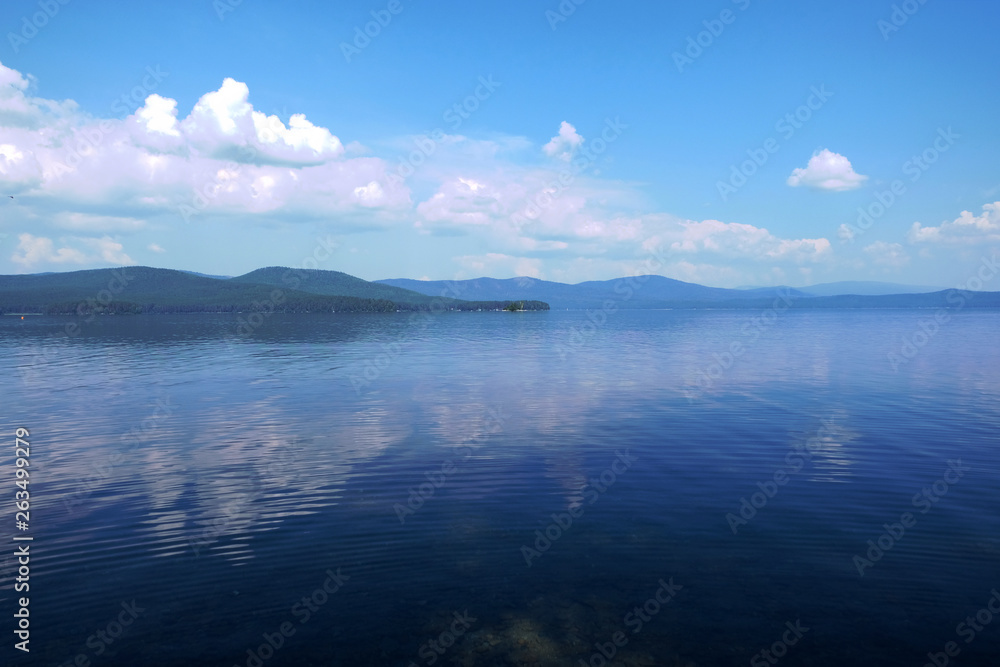 Beautiful blue sky on the lake. Sunset or dawn. White clouds on a blue sky. Natural phenomenon.