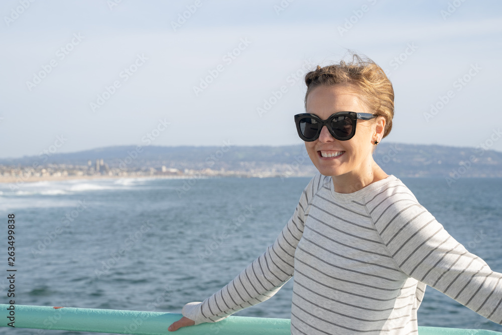 Attractive brunette woman poses on the Manhattan Beach Pier in California on the ocean. Wearing casual clothing Attractive brunette woman poses on the Manhattan Beach Pier in California on the ocean. Wearing casual clothing