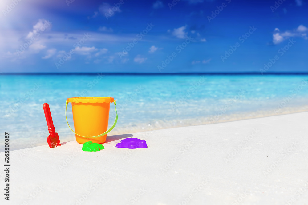 Family vacation concept: colorful toys on a tropical beach with turquoise sea and sunshine Family vacation concept: colorful toys on a tropical beach with turquoise sea and sunshine