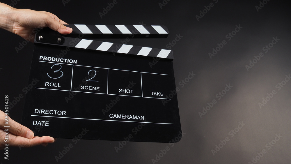 Hand is holding Black clap board or movie slate  use in video production , movie ,film, cinema industry on black background.It have write in number.